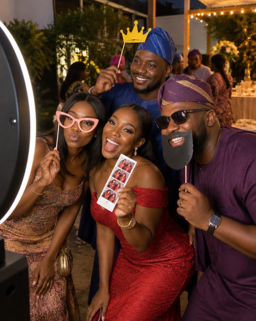 Guests with props and a printed photo strip at a ring-light photo booth during a Lagos birthday party