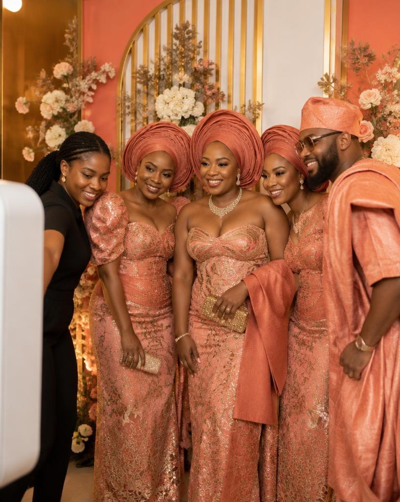 Booth attendant guiding wedding guests in aso-ebi in front of a custom coral backdrop